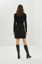 Person wearing a black dress and black knee-high boots on a white background