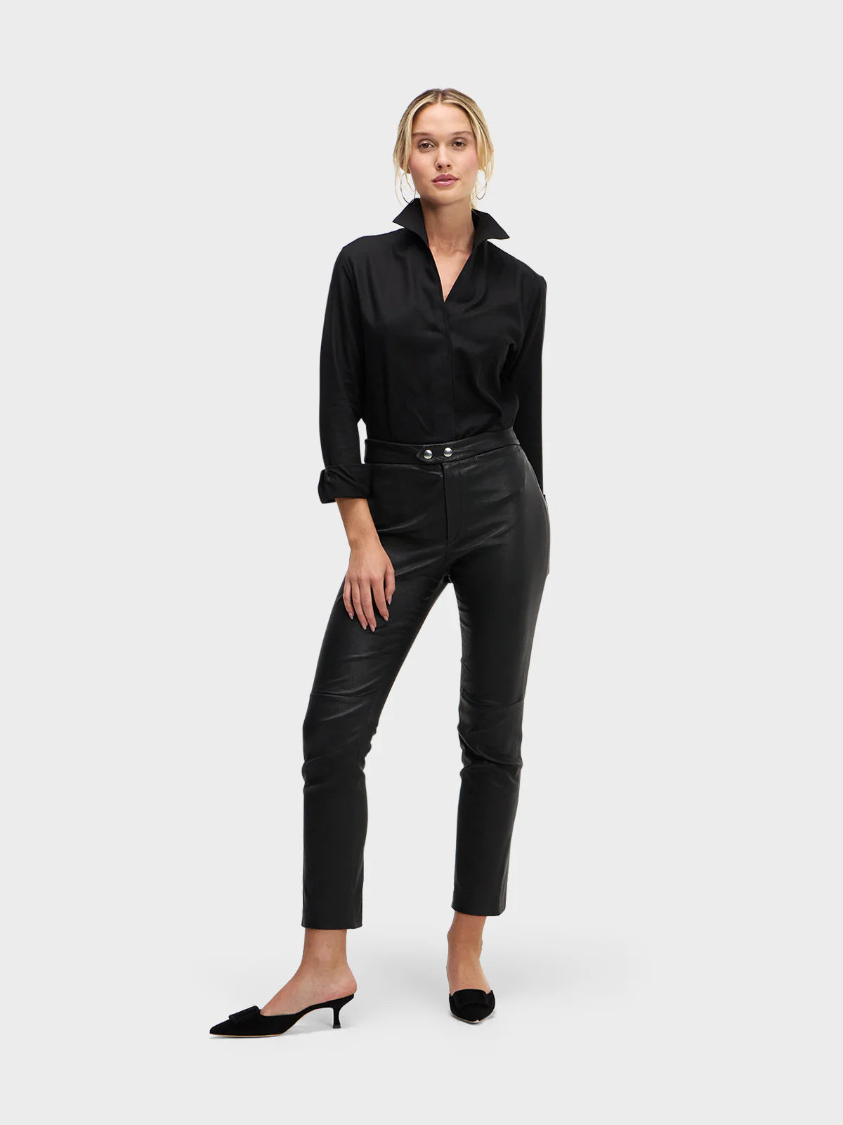 Woman wearing a black blouse and black leather pants on a white background