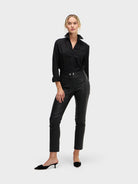 Woman wearing a black blouse and black leather pants on a white background