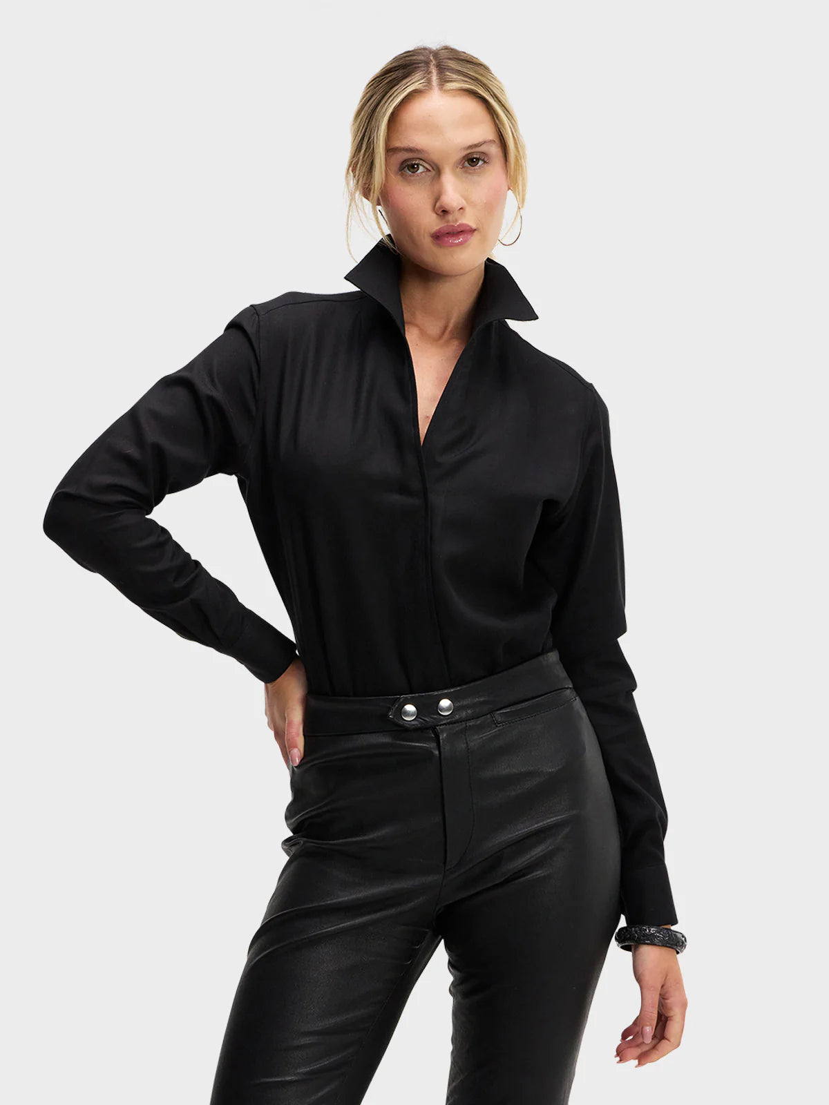 Woman wearing a black long-sleeve top and black pants on a white background