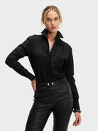 Woman wearing a black long-sleeve top and black pants on a white background